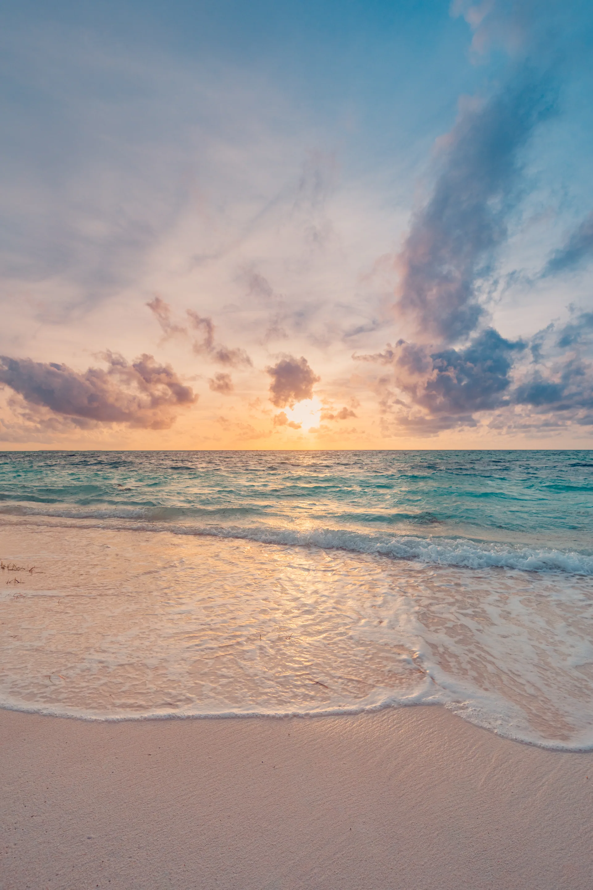 A soft sunset over turquoise surf on a white sand beach